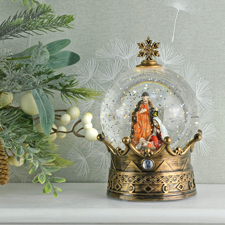 Decorative snow globe with nativity scene on a decorative stand against a light background