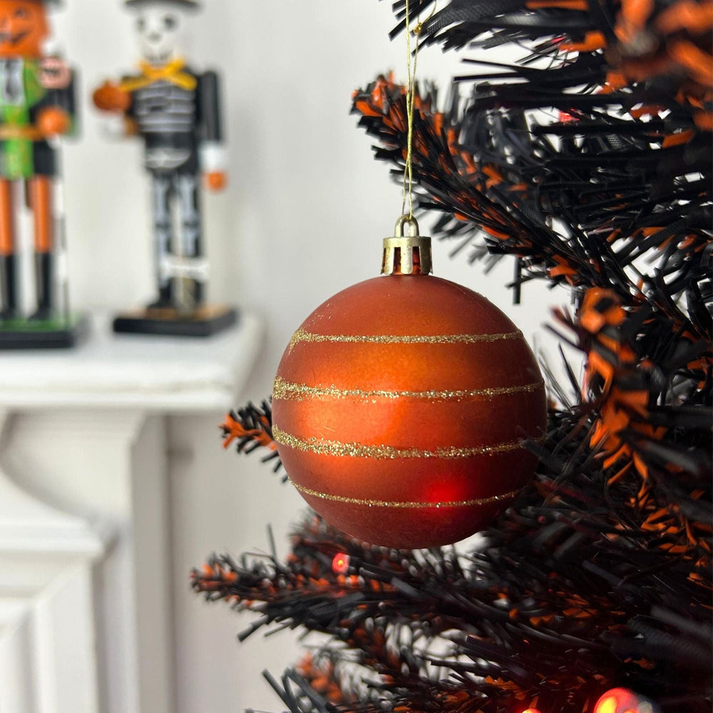Halloween-themed ornament on a black and orange tree with nutcrackers in the background.