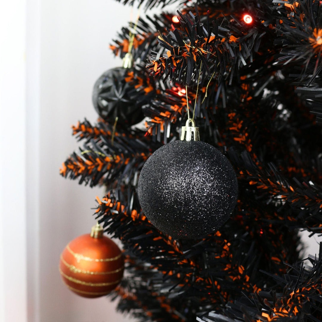 Black Christmas tree with black and orange baubles for halloween on a white background