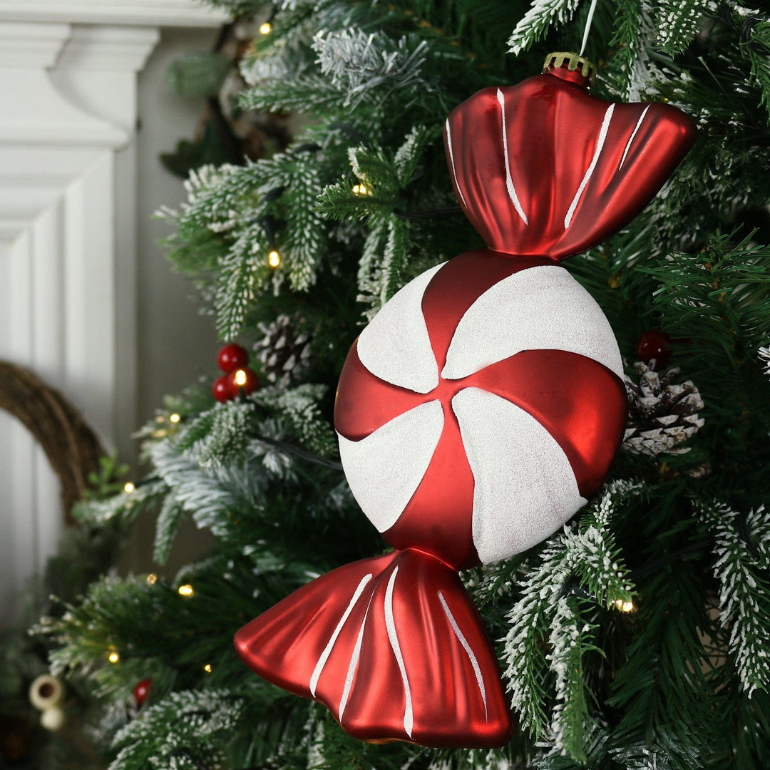 large red and white candy bauble hanging on christmas tree with warm white lights
