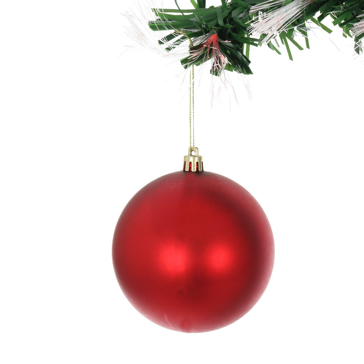 close up shot of large red bauble hanging on christmas tree