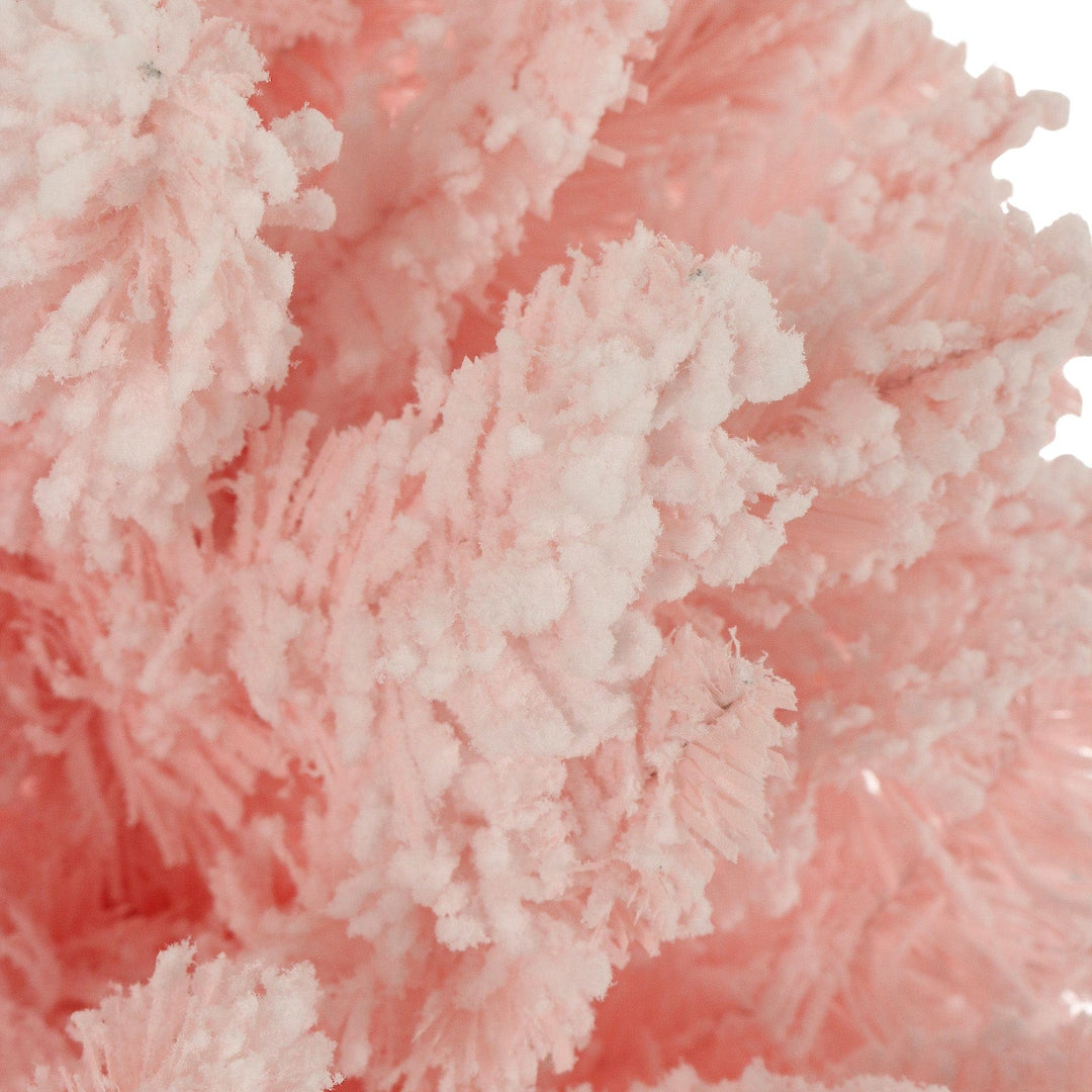 close up of flocked snow on pink christmas tree branches