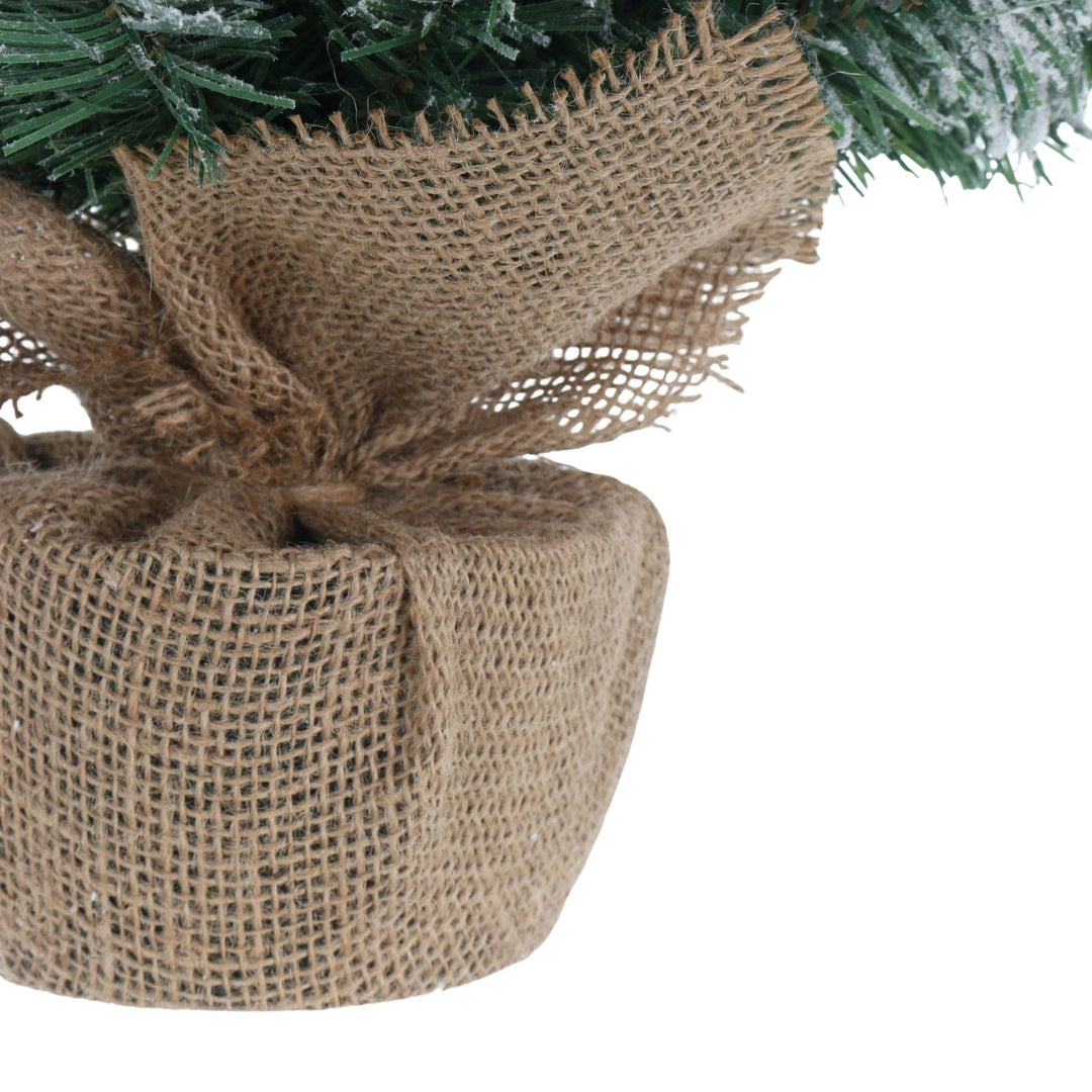 Close-up of a Christmas tree base wrapped in burlap with a white background