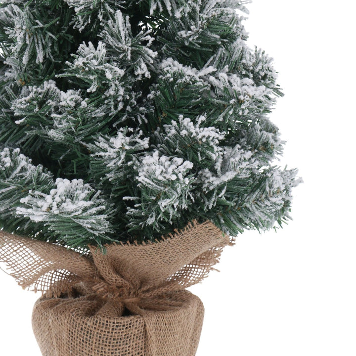 Artificial Christmas tree with snow effect and burlap base on a white background