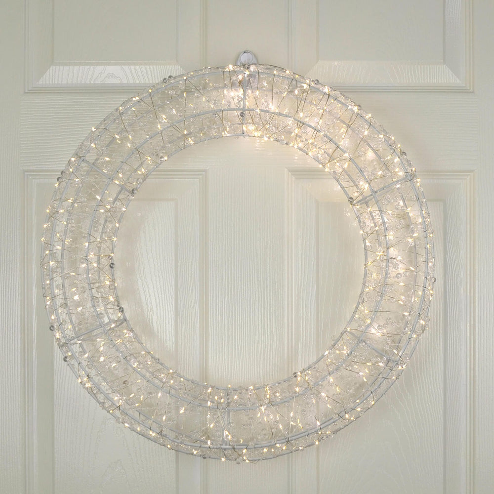 Decorative Christmas wreath with lights on a white wooden door