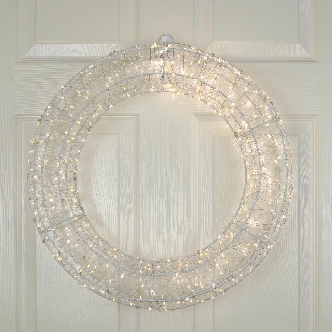 Decorative Christmas wreath with lights on a white wooden door