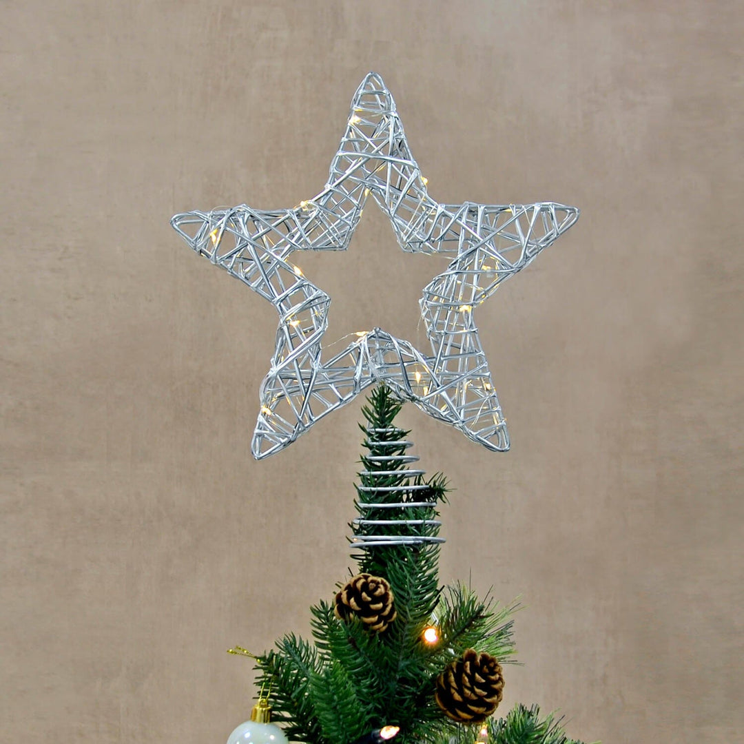 Star shaped tree topper with warm white LED lights and silver wire frame on a green pine Christmas tree
