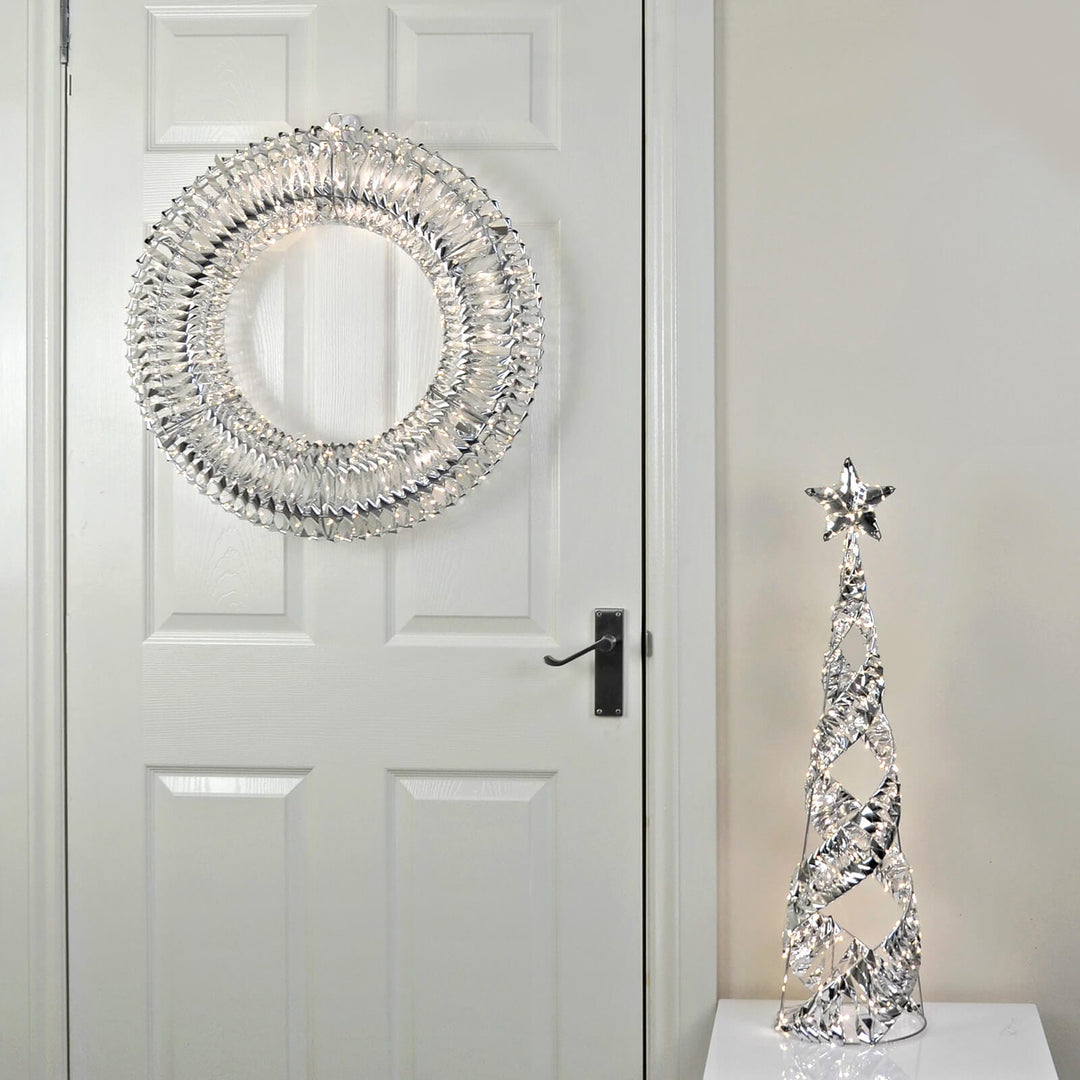 Large silver foil Christmas wreath on a white wooden door with a silver foil Christmas tree