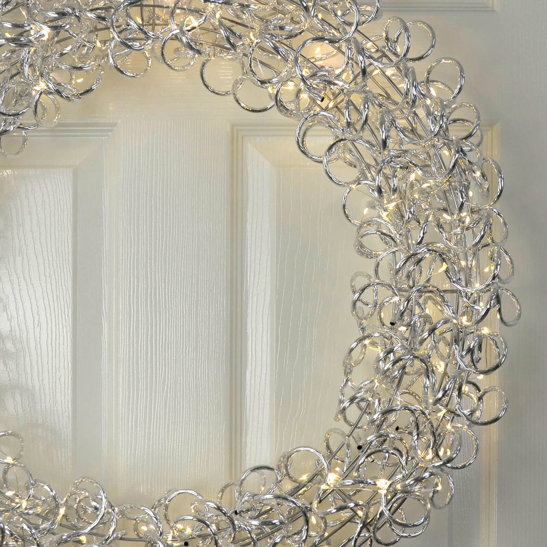 Close up of a warm white LED spiral Christmas wreath on a white wooden door