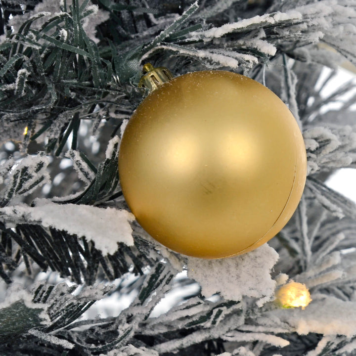 Gold Christmas ball ornament on a frosted tree branch with warm white LED light