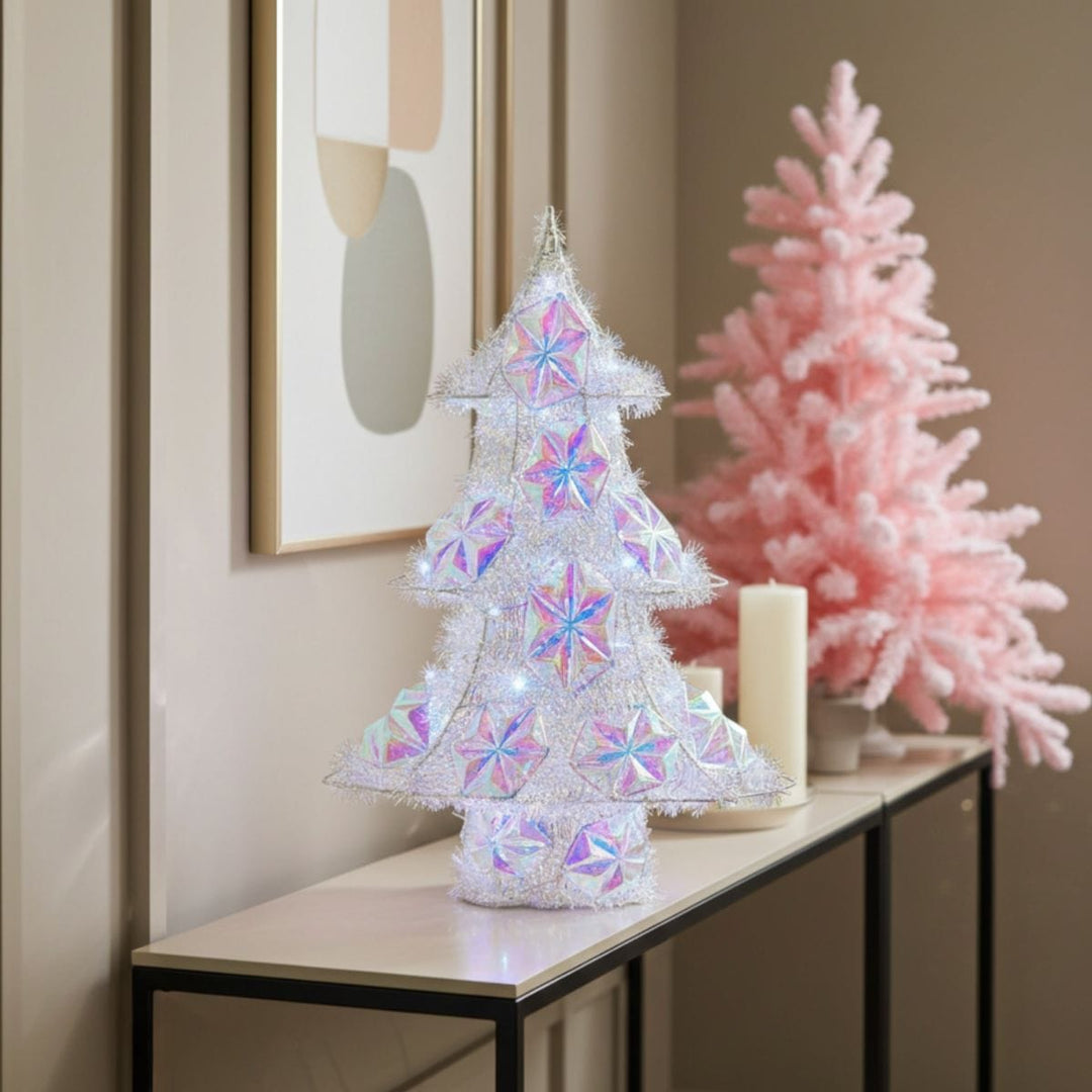 Decorative Christmas trees with colorful lights on a table against a neutral wall.
