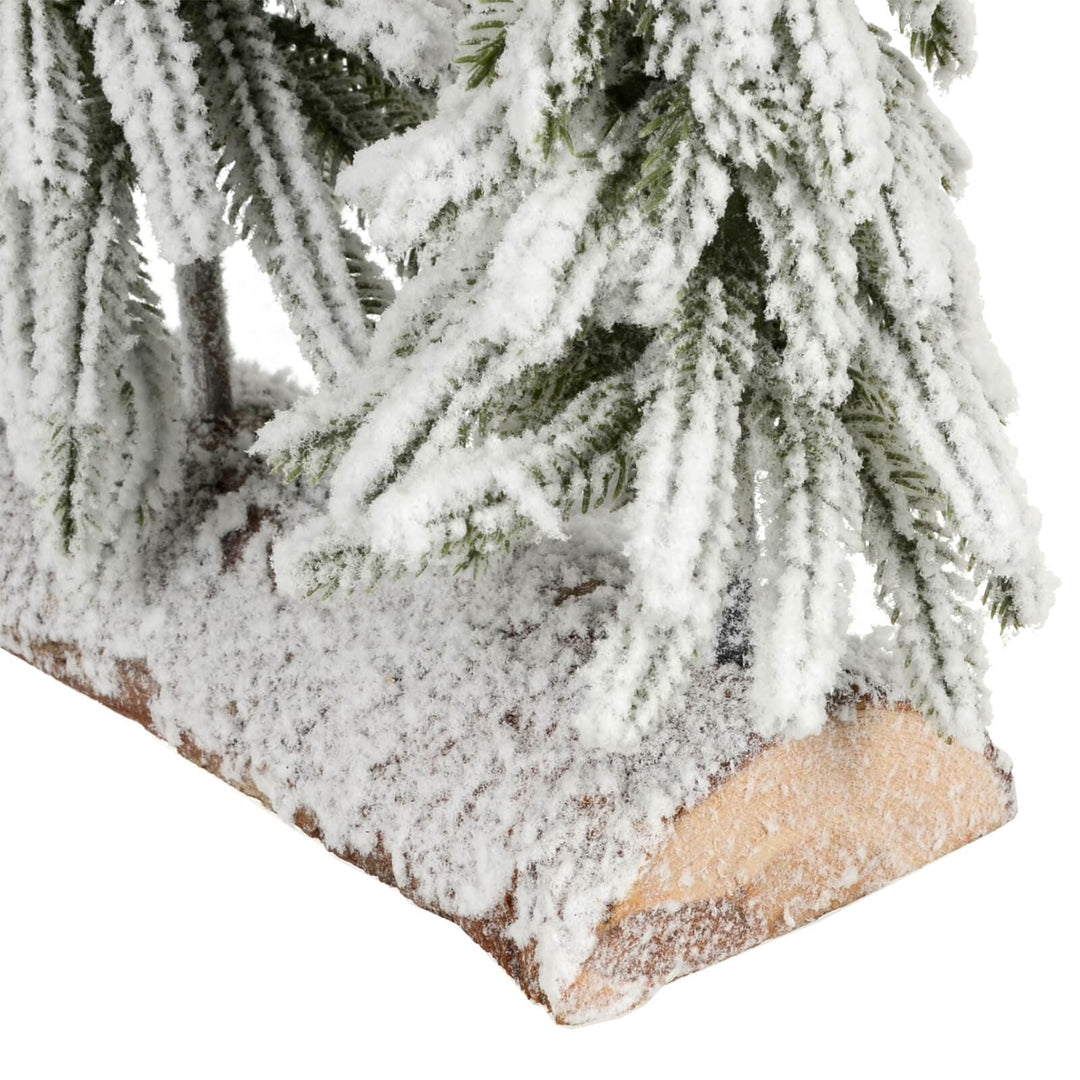 Close up of artificial pine branches and a frosted half log wooden base