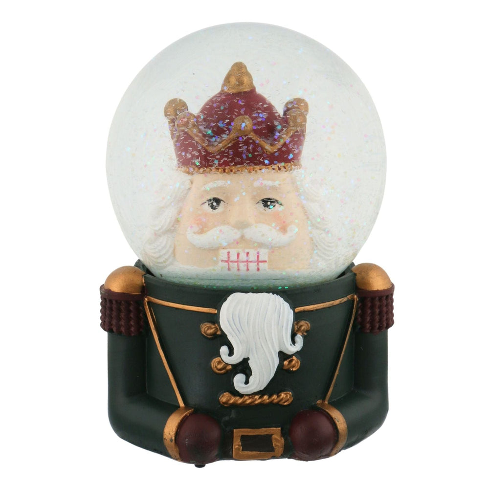 Snow globe with a nutcracker character wearing a crown and green outfit on a white background