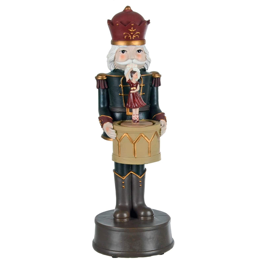 Decorative nutcracker figure holding a drum with ballet dancer on a white background