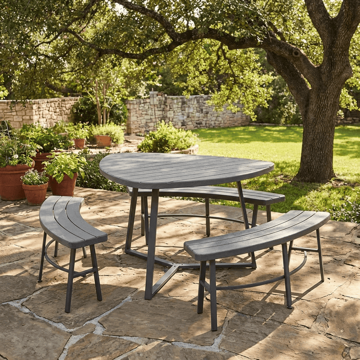 grey picnic set in garden on concrete patio with tree and wall in background