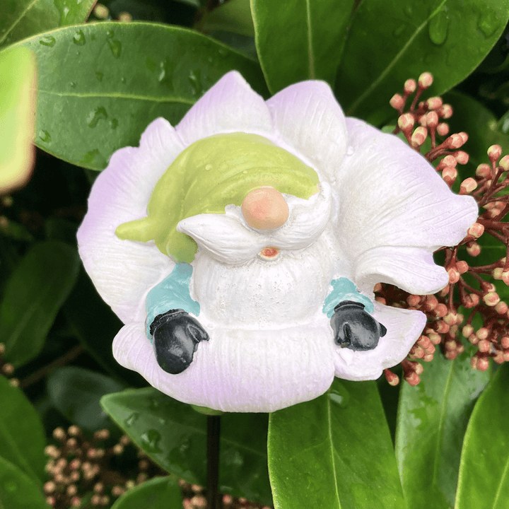 pink flower gnome with green hat in outdoor foliage