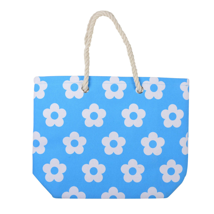 Bright blue beach bag with white flowers and rope handles on a white background