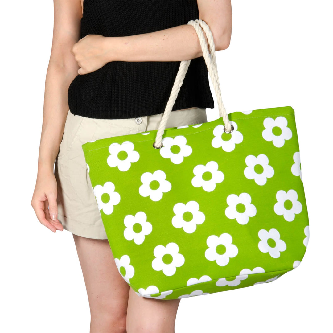 Person holding a bright green beach bag with flower print and white rope handles