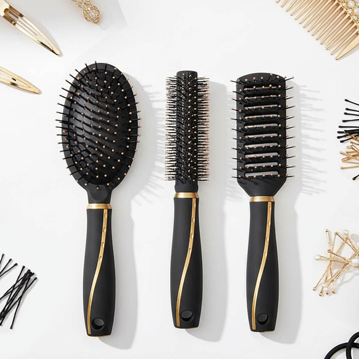 Three black hairbrushes with gold accents on a white background with hair accessories