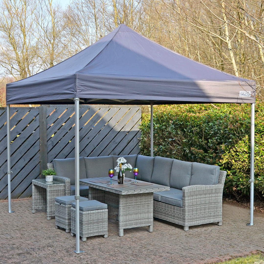 azuma pop up canopy on an outdoor patio space in the sun, with grey rattan furniture on the inside